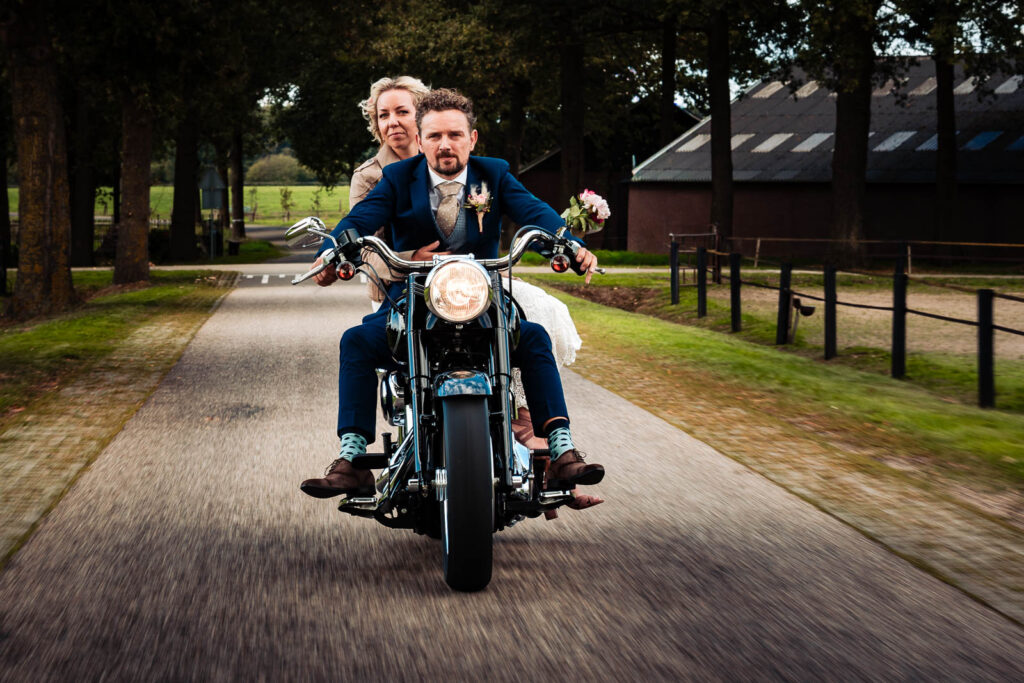 bruid en bruidegom op motor tijdens trouwfotografie met beweging en spontaniteit